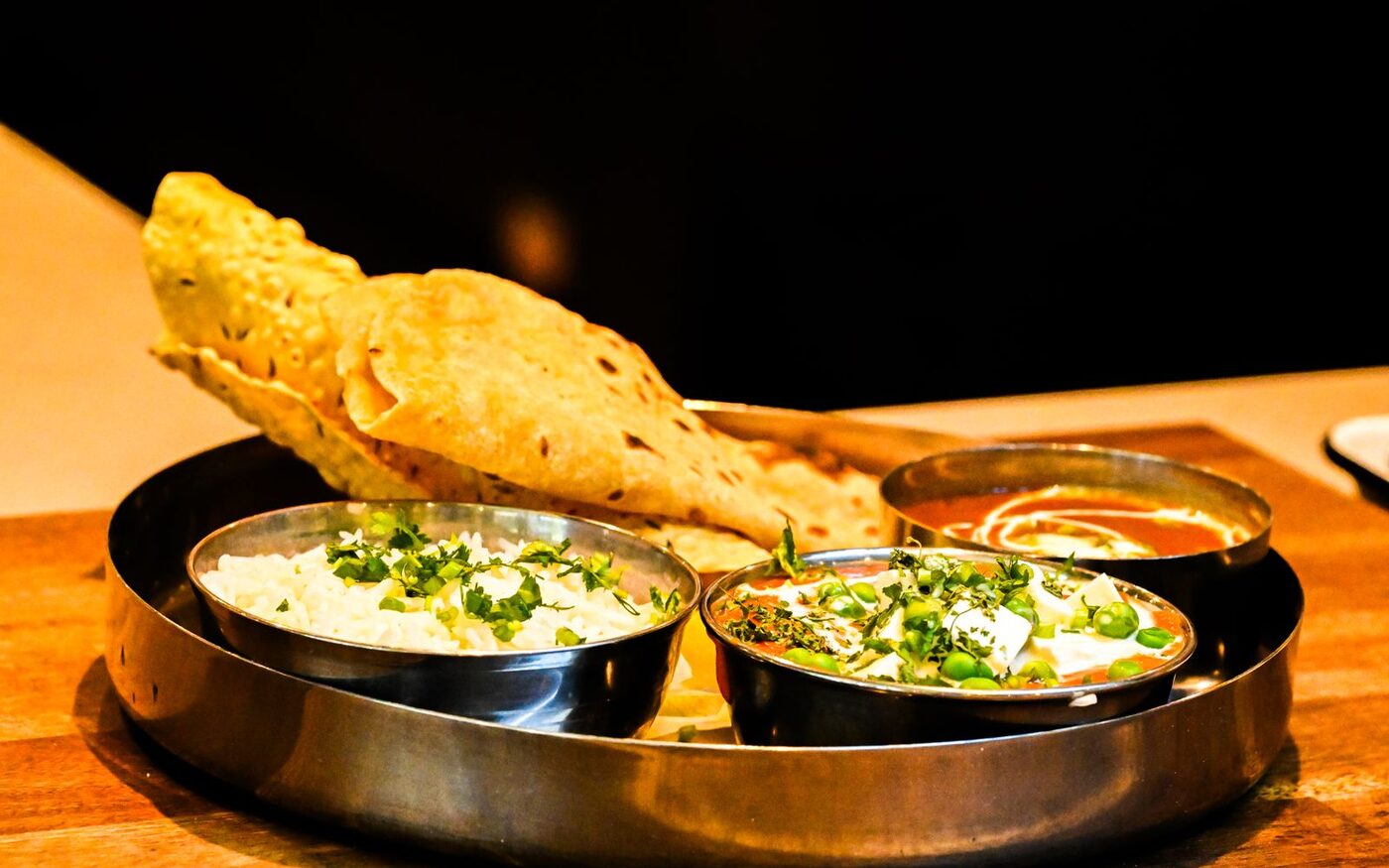 An Indian thali — roti, dal and two curries in steel bowls