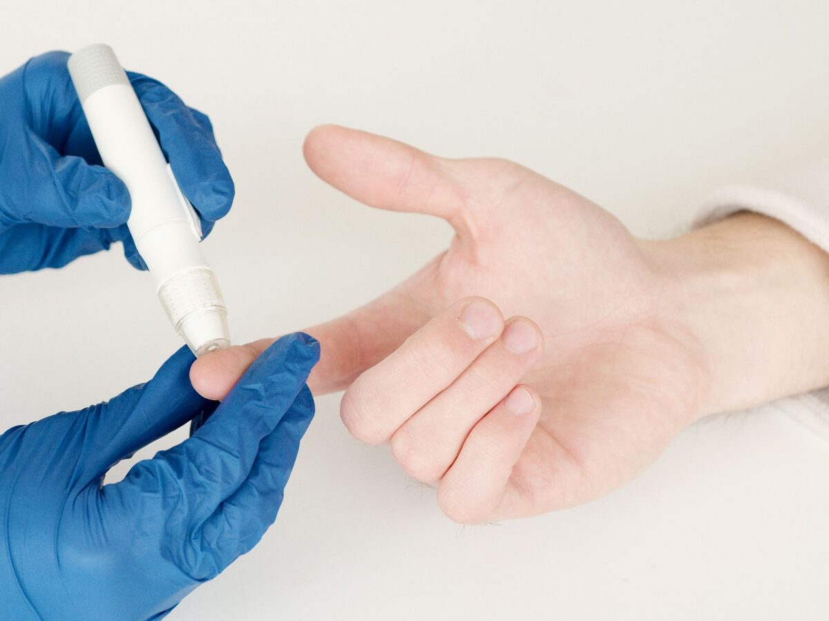 A gloved technician taking a fingerstick blood sample